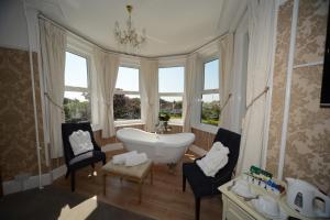 a bathroom with a tub and chairs and windows at Seabrook House Hotel in Hythe