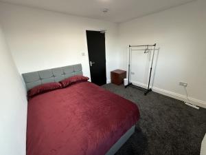 a bedroom with a bed with a red blanket at PLUS PROPERTIES Leeds 6 in Bradford