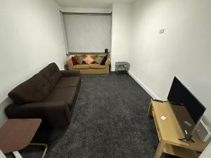 a living room with a couch and a tv at PLUS PROPERTIES Leeds 6 in Bradford