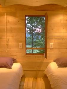 2 łóżka w drewnianym pokoju z oknem w obiekcie Les Cabanes du Tertre w mieście Urval