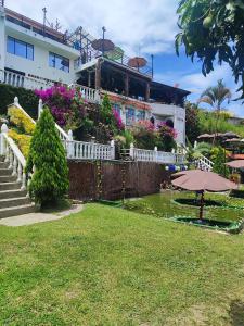 ein Haus mit einem weißen Zaun und einem Rasen mit einem Sonnenschirm in der Unterkunft Ecohotel Java in Manizales