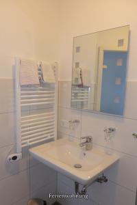 a white bathroom with a sink and a mirror at Pension Haus Linden in Winterberg