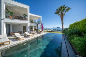 a house with a swimming pool and a palm tree at Villa Matie Bodrum Views in Bodrum City