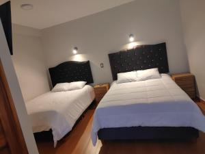 a bedroom with two beds with white sheets at Hotel pumaexplorer in Urubamba