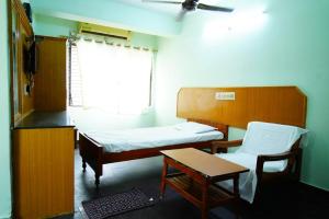a room with two beds and a table and a window at Balaji inn in Anantapur
