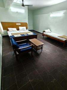 a room with two beds and a table in it at Balaji inn in Anantapur