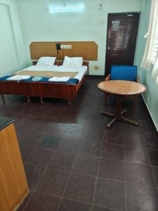 a bedroom with a bed and a table and a chair at Balaji inn in Anantapur +4 photos