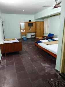 a room with two beds and a desk and a tv at Balaji inn in Anantapur