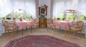 a dining room with pink tables and chairs and windows at Pension Haus Linden in Winterberg +15 photos