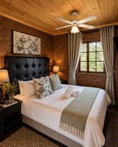 a bedroom with a large bed with a ceiling fan at Linglela Lodge in Estcourt