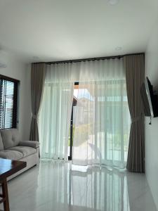 a living room with a couch and a large window at Green Mountain View villas Koh samui in Plai Laem