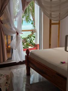 a bedroom with a bed and a view of the ocean at Nisandra Beach Hotel in Nungwi