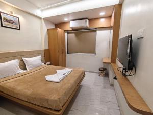 a bedroom with a bed with a flat screen tv at Hotel Sai Praatham in Shirdi
