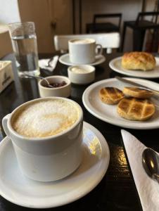 a table with a cup of coffee and plates of food at Posada Las Chacras in Ciudad Lujan de Cuyo +3 photos