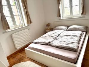 an unmade bed in a room with two windows at Idyllische Auszeit am Waldrand in Weiler