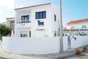a white house with a black cow on the side of it at O Tourinho Baleal in Baleal