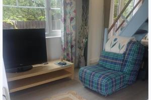 a living room with a tv and a chair at Inviting 1-Bed Cottage in Pontypridd in Pontypridd +11 photos