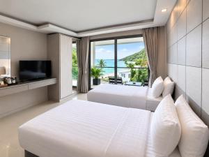 a bedroom with two beds and a large window at Sunset Beach Hotel - Adults Only in Haad Rin