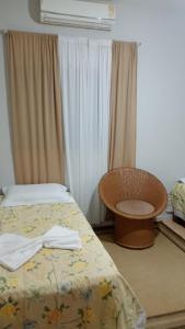 a bedroom with a bed and a chair and curtains at Primeiro Hotel in Ilha Solteira