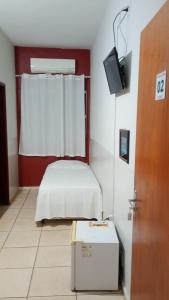 a room with a bed and a tv in it at Primeiro Hotel in Ilha Solteira