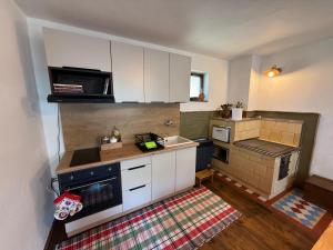 a small kitchen with white cabinets and a sink at Dvor u Hrivka in Heľpa +8 photos
