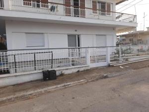 a white building with a fence next to a street at Paulos&Mary Apartment in Flogita