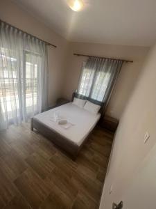 a bedroom with a bed with white sheets and windows at Paulos&Mary Apartment in Flogita