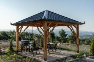 a gazebo with a table and chairs and a grill at Golden view Villa in Prishtinë
