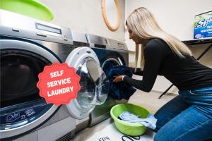 a woman loading a washing machine in a laundry room at Hotel COSMEA - Your Dolomites & Honeymoon experience in Ortisei