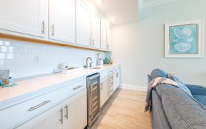 a kitchen with white cabinets and a couch at Phoenix Gulf Towers 706 condo in Gulf Shores