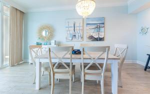 a dining room with a white table and chairs at Phoenix Gulf Towers 706 condo in Gulf Shores