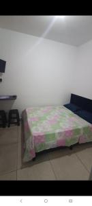 a bedroom with a bed with a green and purple blanket at Hostel Viracopos in Campinas