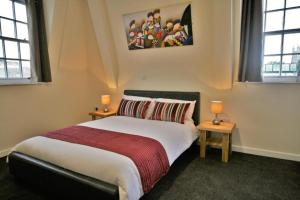 a bedroom with a large bed with two tables and two windows at Central Hotel Gloucester in Gloucester
