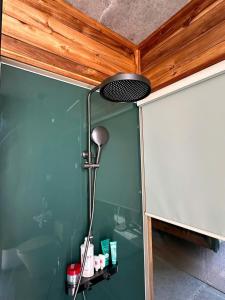 a shower with a light on a green wall at Chum Home in Thanh Ðông (1) +8 photos