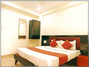 a bedroom with a large bed with orange and white pillows at Udupi Grand Lodging and Boarding in Chākan +15 photos