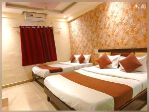 two beds in a hotel room with a red curtain at Udupi Grand Lodging and Boarding in Chākan