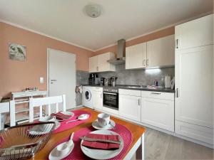 a kitchen with a table and a kitchen with white cabinets at Ferienhaus SweetHome - eingezäunter Garten - 3 Hunde willkommen - ruhige Sackgasse in Bad Sachsa