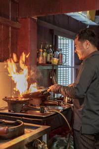 a man is cooking food on a grill at Sambor Village Hotel in Kompong Thom