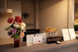 a vase of flowers sitting on a counter with books at 777 Food & Bed in Chiang Rai
