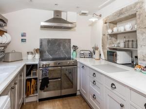 a kitchen with white cabinets and a stove top oven at Earsdon Cottage in Ireby +17 photos