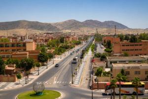 a street in a city with mountains in the background at Hôtel Aguelmam in Khenifra +15 photos