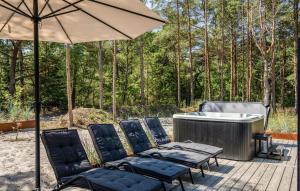 a hot tub with chairs and an umbrella on a deck at Nice Home In Nexø With Sauna in Neksø