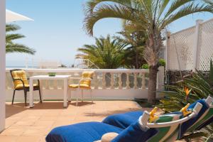 a person laying on a balcony with a table and chairs at Apartments Gina y Vista Oceano in Puerto del Carmen