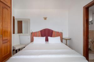 a bedroom with a white bed with a red headboard at Apartments Gina y Vista Oceano in Puerto del Carmen