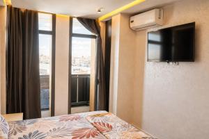 a bedroom with a bed and a tv and a window at Hôtel Aguelmam in Khenifra