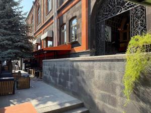 a building with a stone wall next to a sidewalk at Araks Hotel Complex in Gyumri