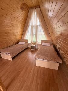 two beds in a wooden room with a window at Green zone Aframe in Qusar