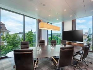 a conference room with a table and chairs and large windows at Mövenpick Hotel Basel in Basel