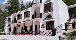 a large white building with red windows at Hotel Dharali Nature In Dharali in Gangnāni