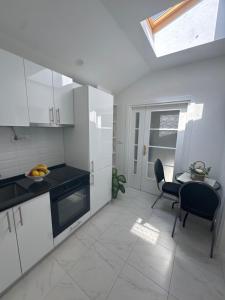a kitchen with white cabinets and a table and a window at Herz Apartmani in Igalo